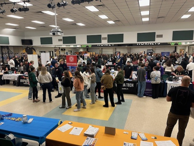 Wide view of the Nassau County School District 2026 College & Career Fair showing a large crowd of students, families, and vendors filling the cafeteria.