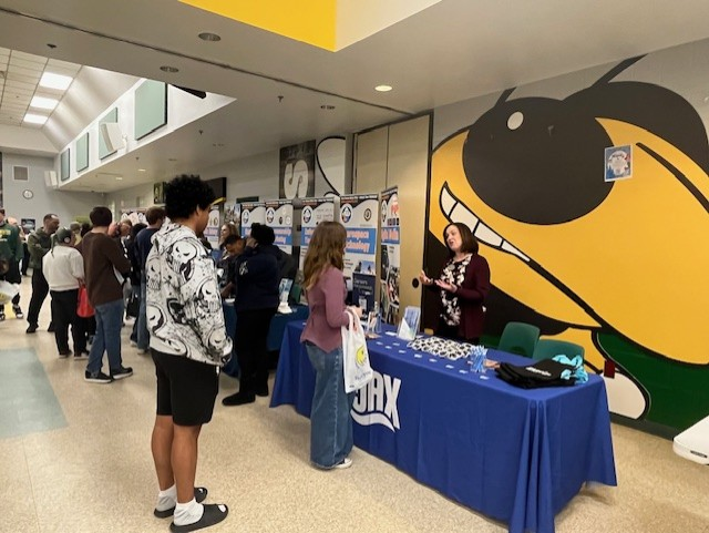 Students and vendors interact along a row of career and college booths set up inside the Yulee High School cafeteria.