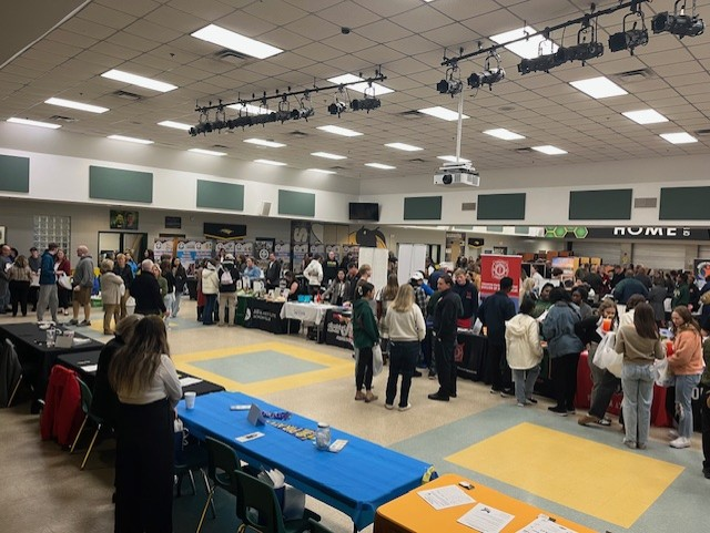 Another wide-angle view shows students moving between multiple college, career, and industry booths during the district career fair.