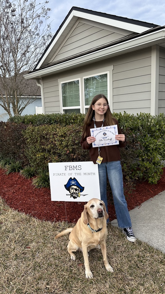 Photo of Ella K and her dog holding the Student of the Month sign.