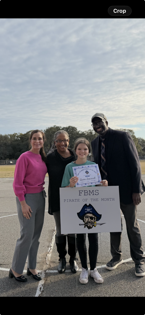 Picture of Quinn S., Dr. Crawford, Ms. West, and Mr. Hardy behind the student of the month sign.