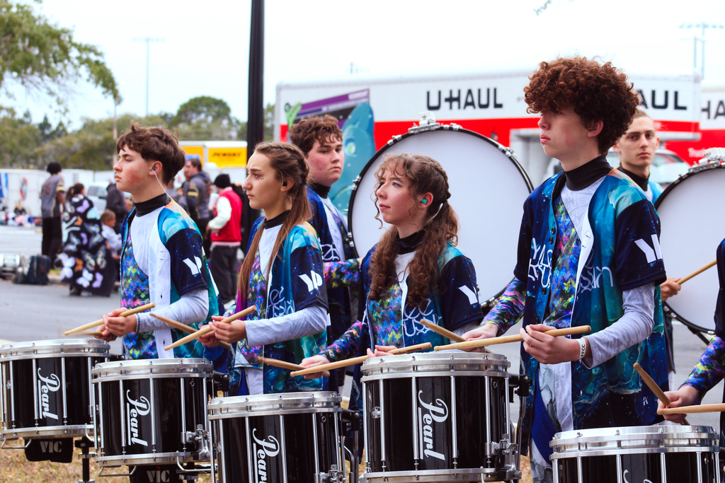 Yulee High School drumline stands in formation outdoors playing snare drums during competition