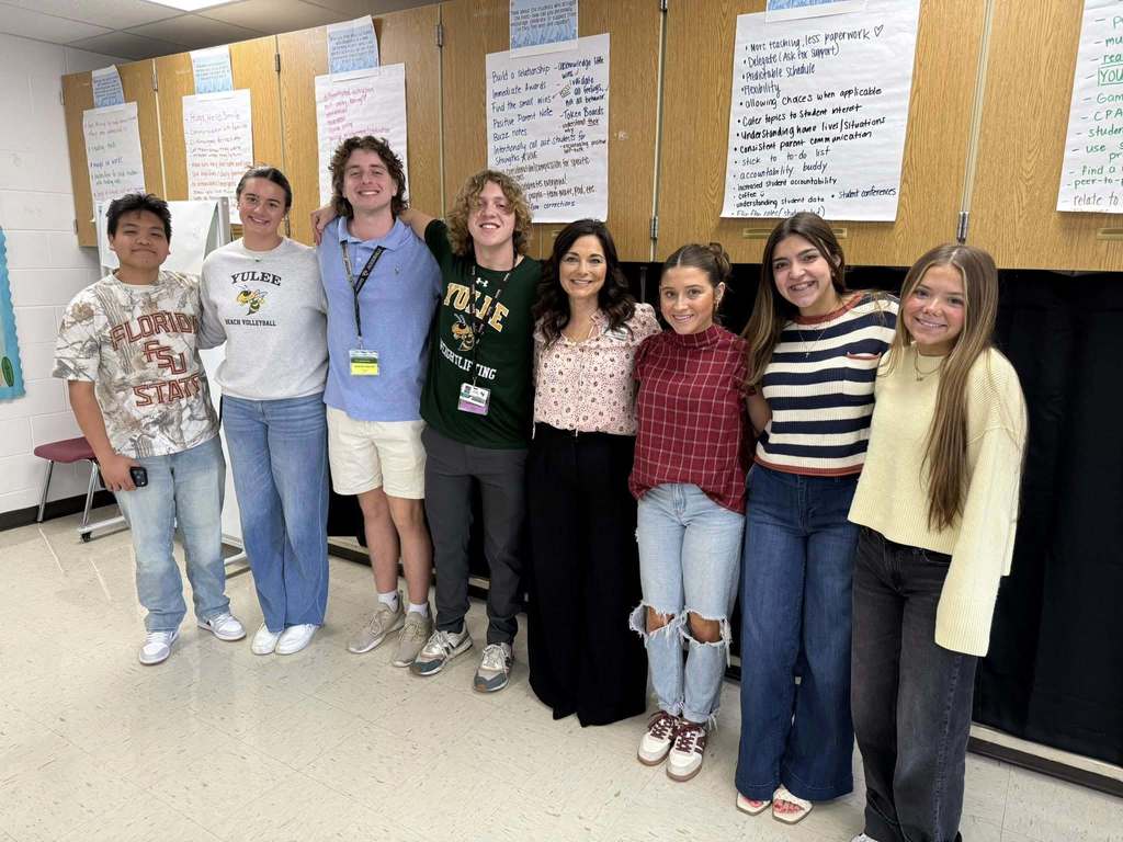 A group photo of Yulee High School FFEA members and primary teachers smiling together inside a classroom following their observation visit.