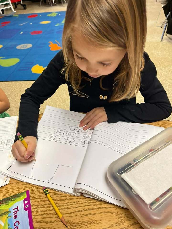 Student writing sentences in her journal. 