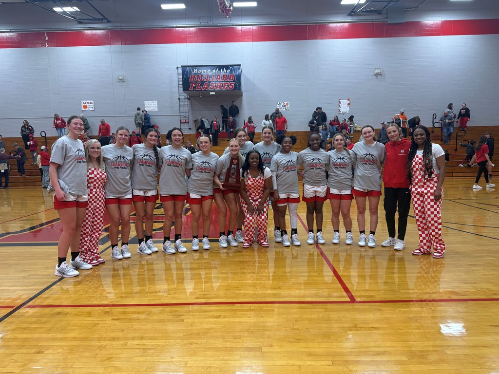 Girls Basketball team posting for photo with coaches and trophy.