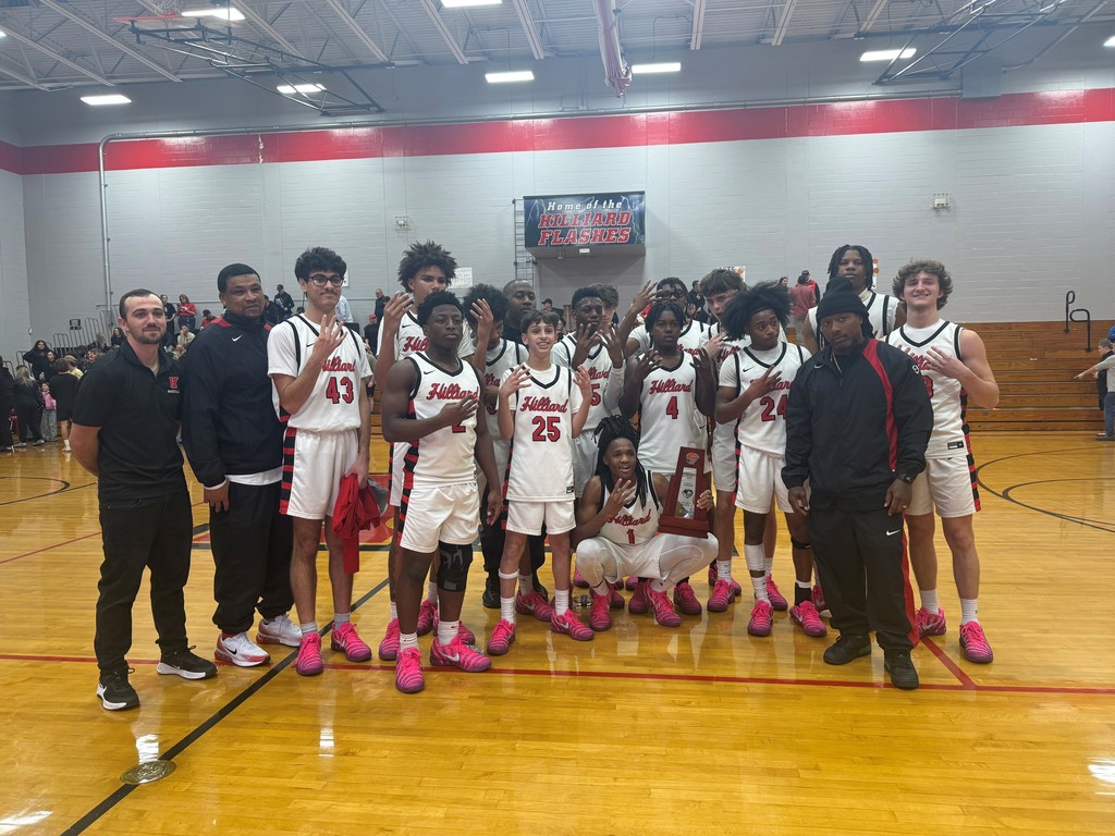 Boys basketball team posing for photo with coaches and trophy.