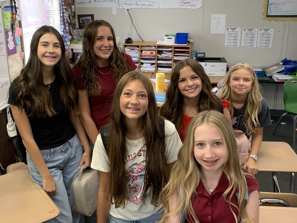 Student journalists smile for the camera inside their classroom. 