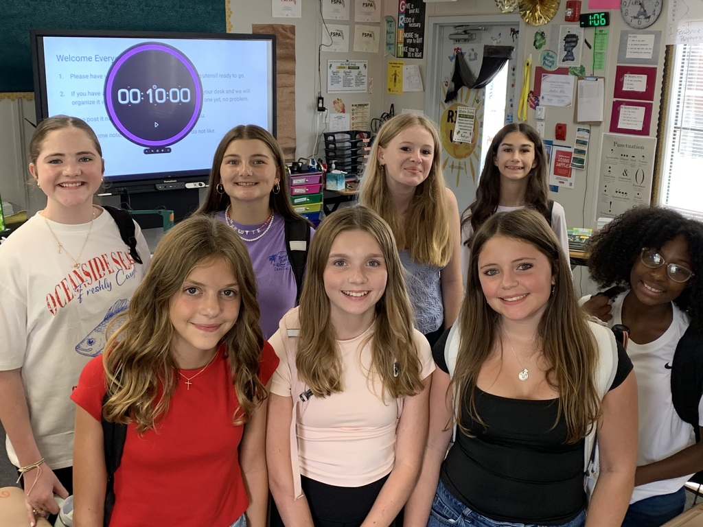 Student journalists smile for the camera in their classroom. 