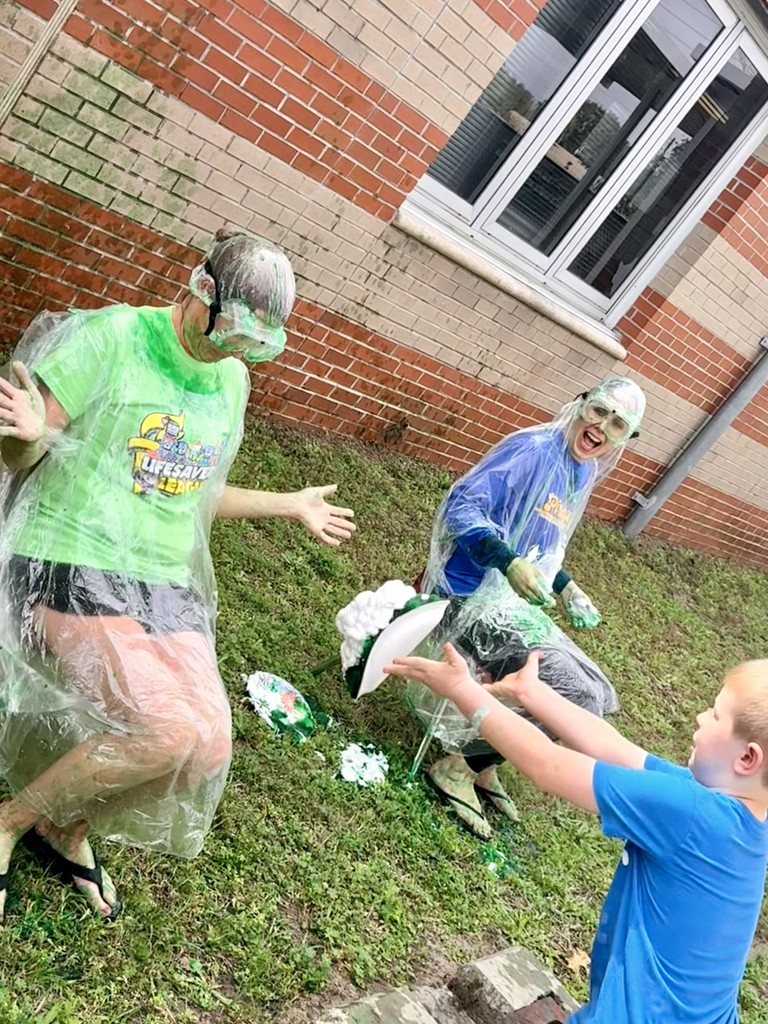 Student throwing shaving cream pie at Ms. Trammell.