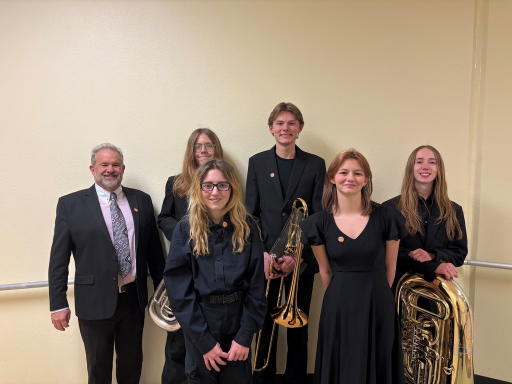 Band Director and students posing with instruments.