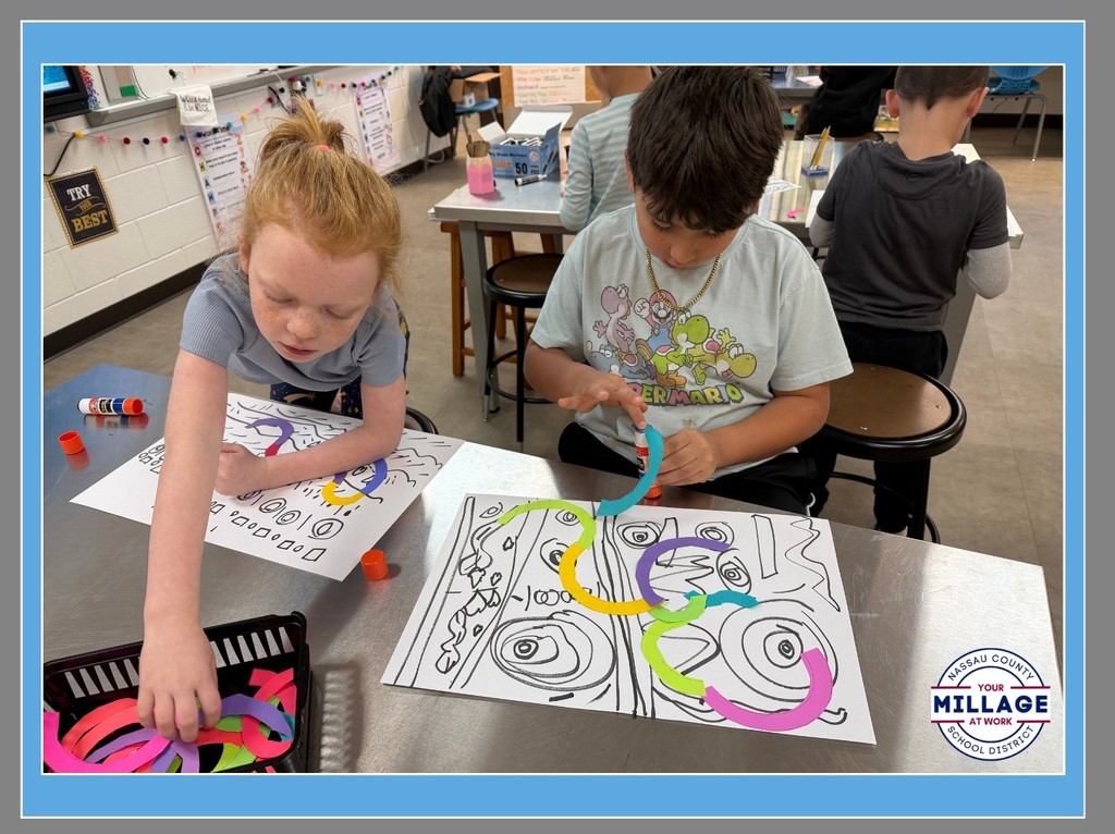 Two elementary students sit at a classroom table, focused on creating vibrant art. They are using colorful paper to make swirling, looped lines on white paper, surrounded by other art supplies in a bright classroom setting.
