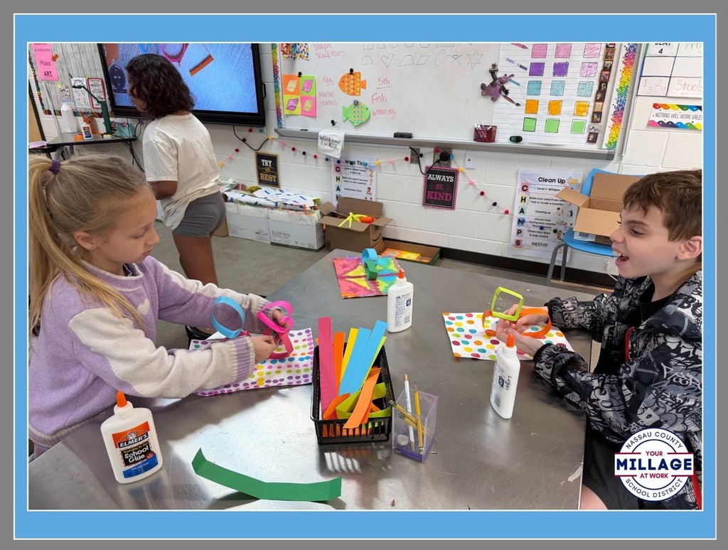 Elementary students at Wildlight Elementary engaged in a hands-on art activity, cutting and assembling bright paper shapes at a shared table.