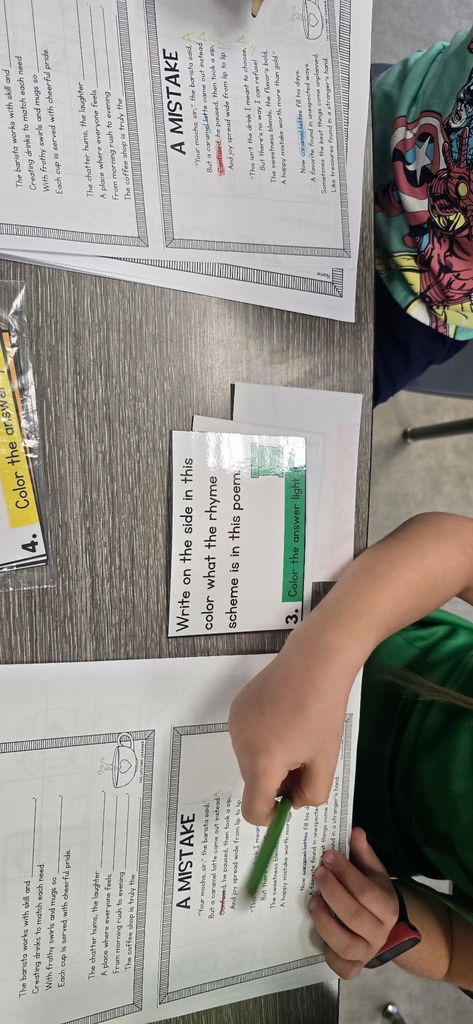 A close-up of a student's hands holding a pencil over their completed poetry worksheet, ready to add the finishing touches.