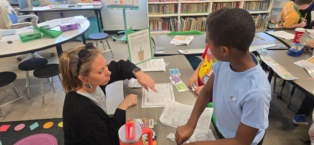 Students working in a classroom transformed for Poetry Week, with Starbucks-themed decorations and instructional materials on the tables.