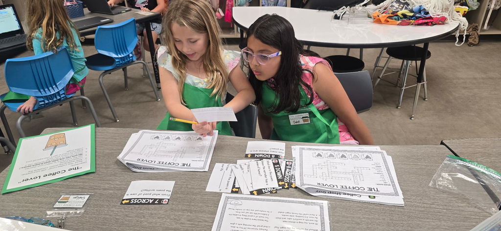 Students working in a classroom transformed for Poetry Week, with Starbucks-themed decorations and instructional materials on the tables.