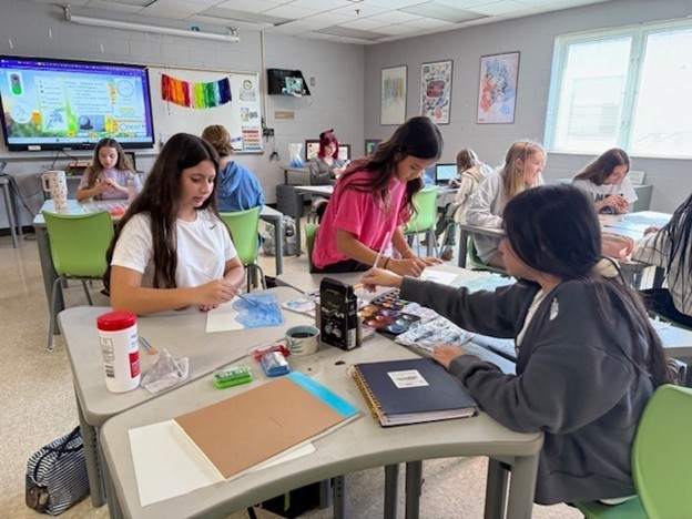 Multiple students learn through painting at their learning station on Fun Friday in art class. 