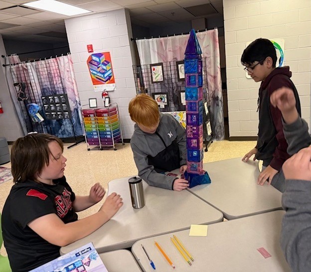 Students learn with magnetic building blocks and build a tower together at their learning station. 