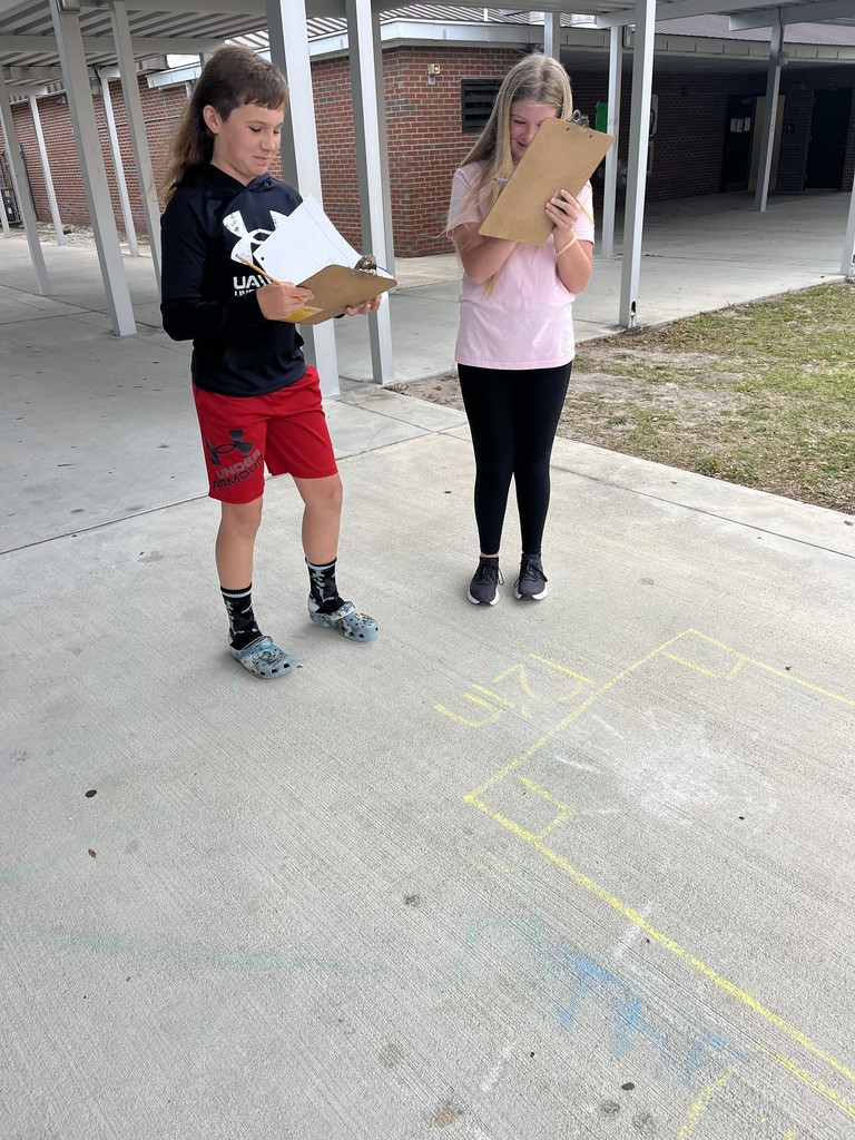 Students working math problems on the concrete.