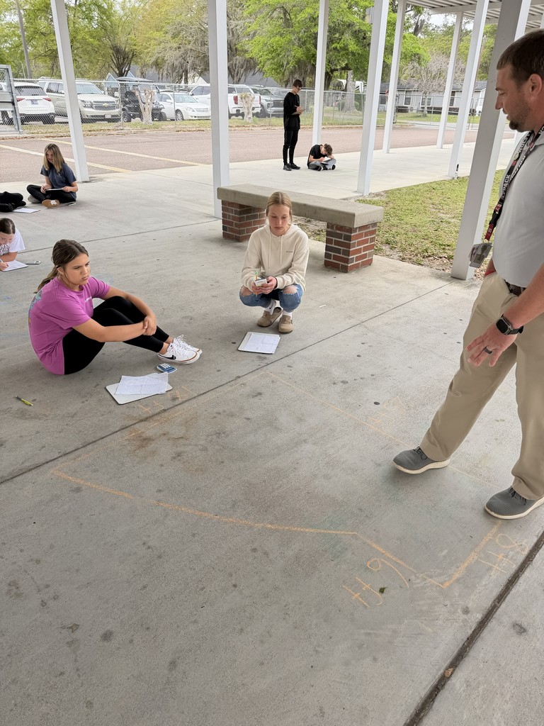 Students working math problems on the concrete.