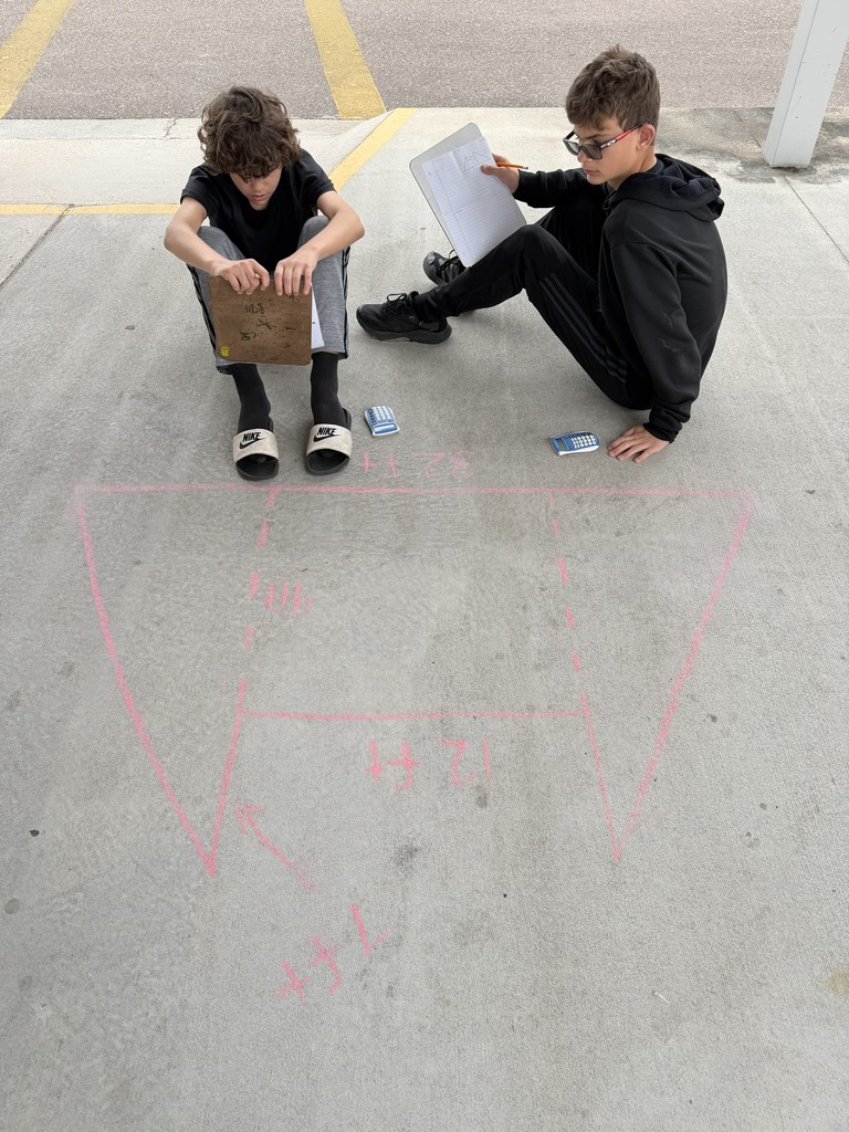 Students working math problems on the concrete.