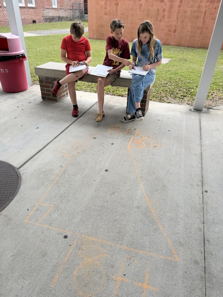 Students working math problems on the concrete.