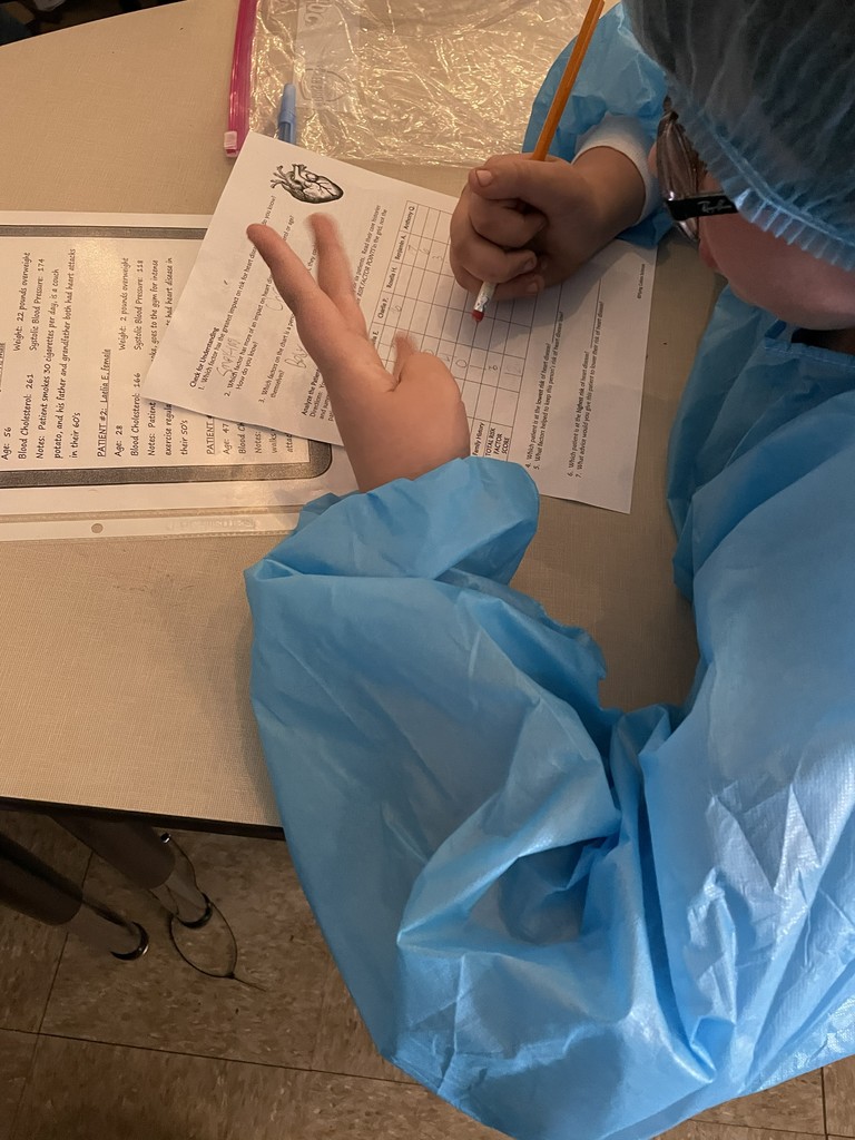 Students dressed in hospital scurbs working at their desk.