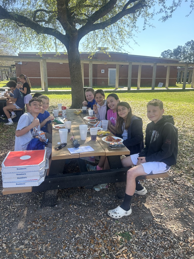 Students sitting at a picnic table enjoying a pizza party