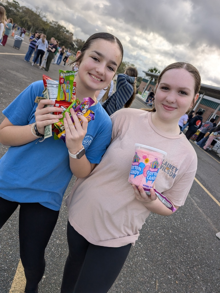 Two students showing off their treats that they purchased at infraction free day smiling. Cloudy skies. 