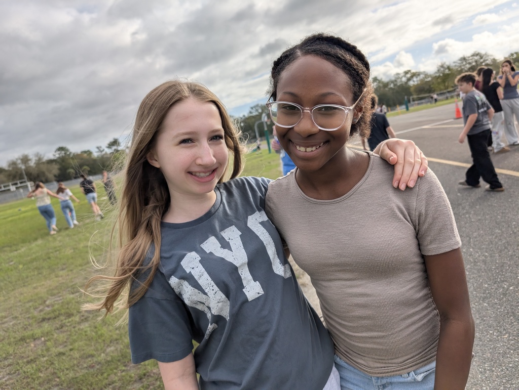Two students smile for the camera at infraction free day with other students playing in the background. 