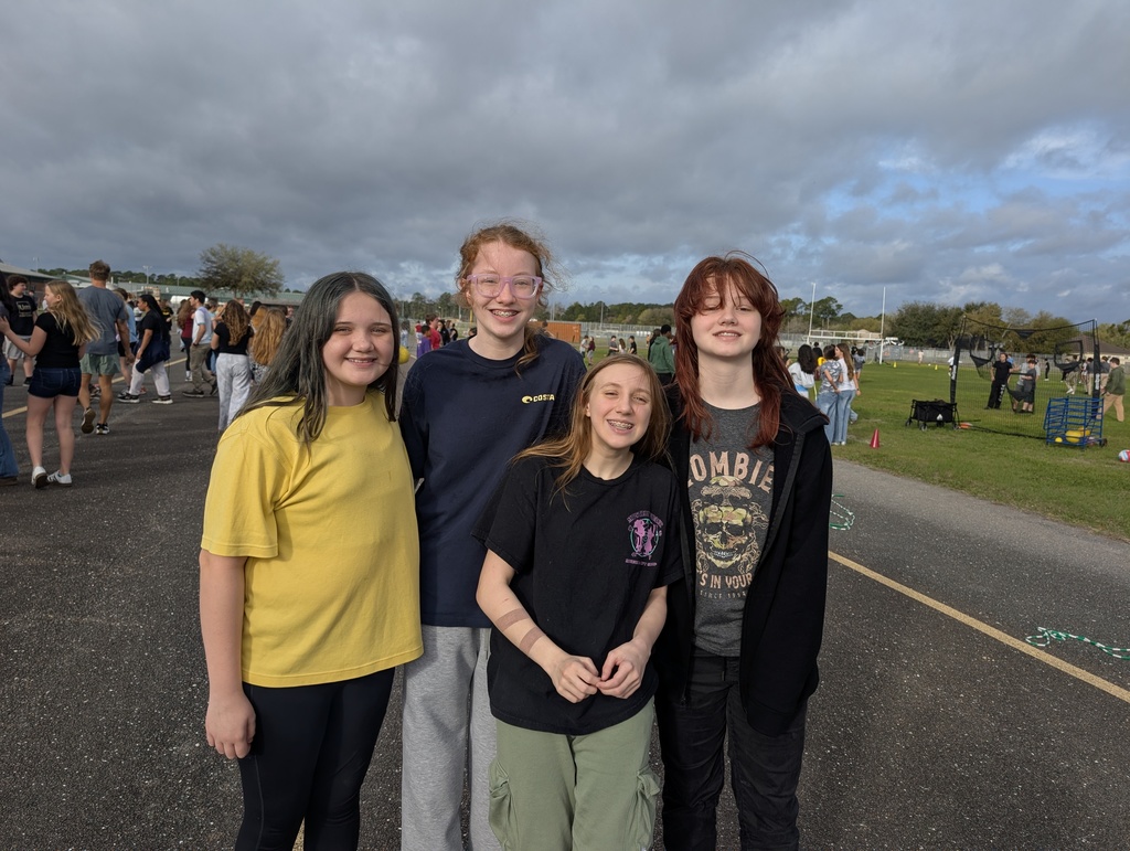 Four students smile for the camera at infraction free day. Cloudy skies. 