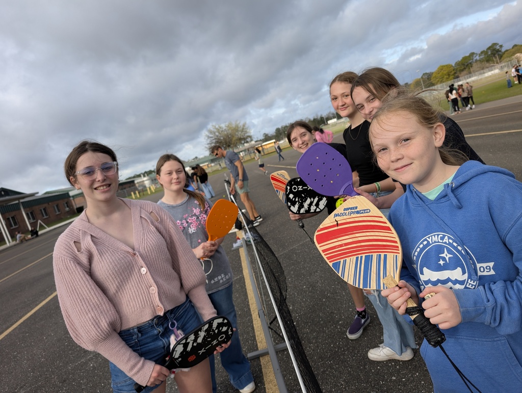 Six students pause their game of pickleball at infraction free day to take a smiling picture