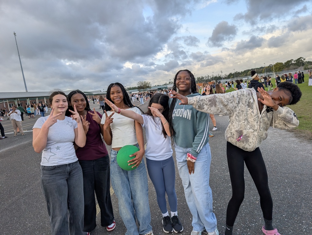 Six students pose for a silly picture, smiling and dabbing and throwing up peace signs as they pause their game of basketball at infraction free day.