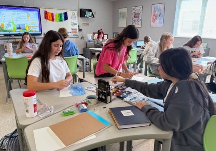 Students hard a work at their desk completing a watercolor painting. 