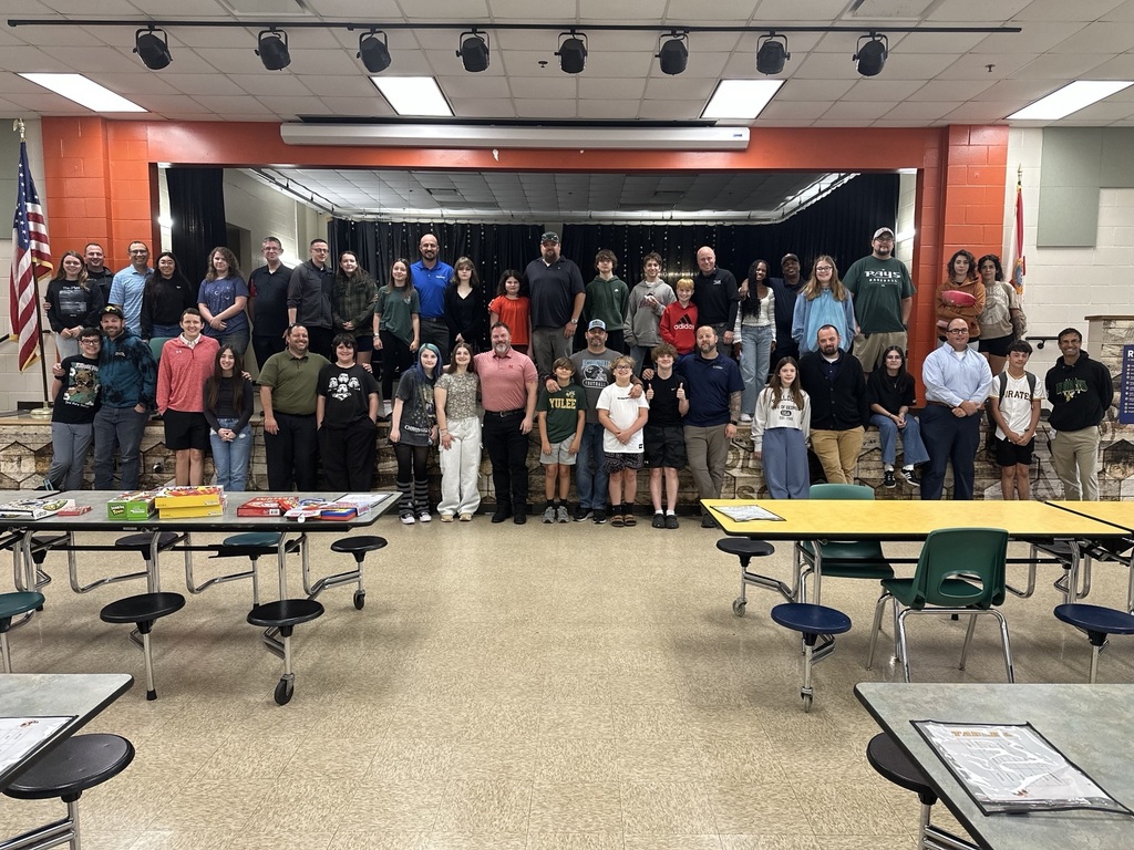 Dads and their students pose for the camera in front of and on top of the cafeteria stage at the final all pro dads meeting of the year. 