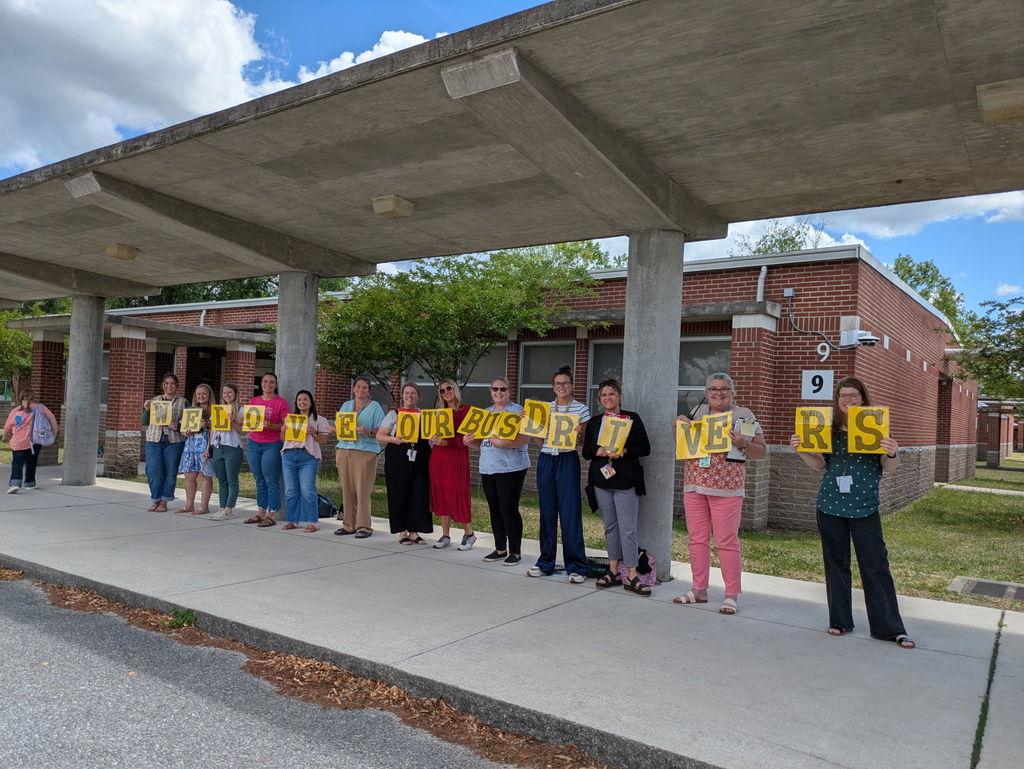 Staff holding “We Love Our Bus Drivers” sign