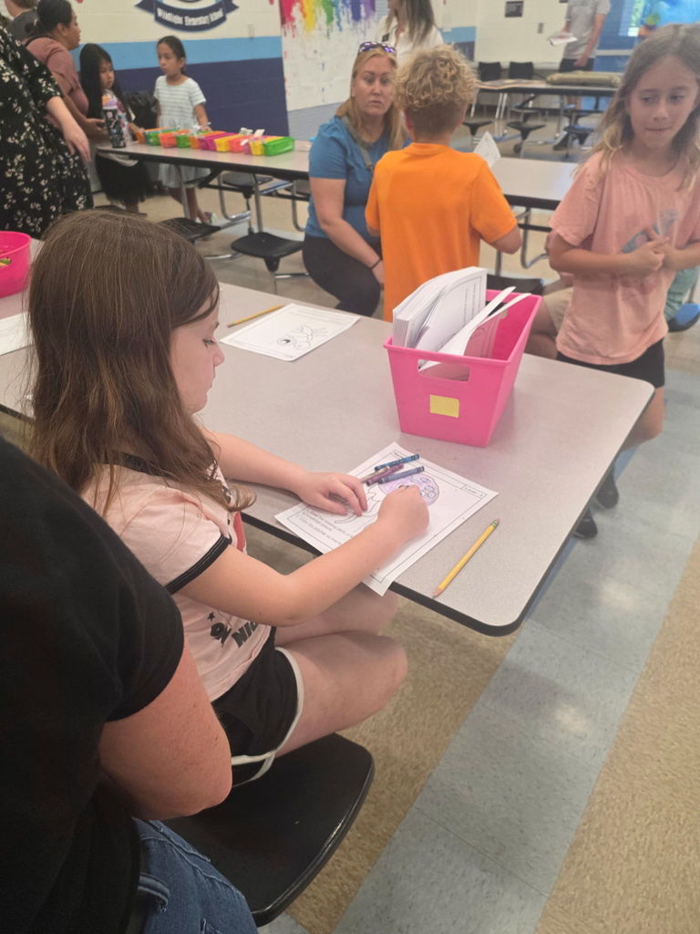 A young student focused on their work, sitting at a table and using colorful markers to create a drawing.