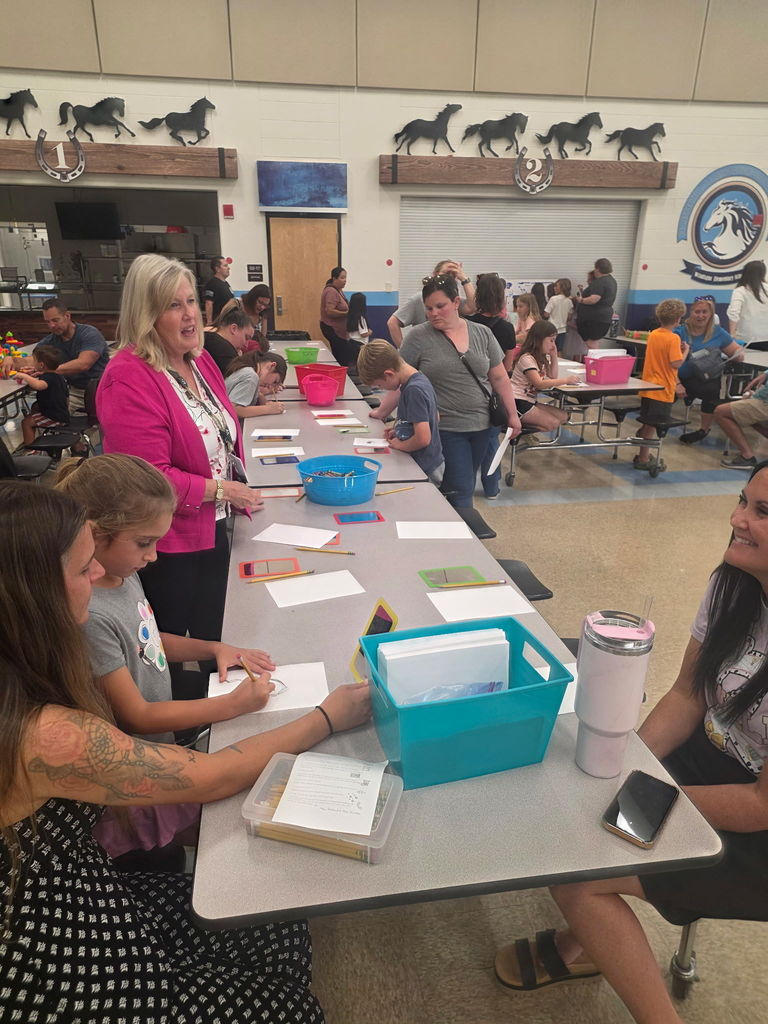 Staff members and volunteers welcoming families at a decorated table at the entrance of the Art Night event.