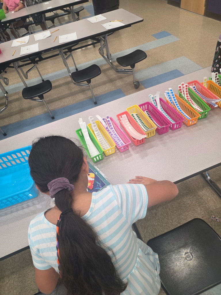 A young student focused on their work, sitting at a table and using colorful markers to create a drawing.