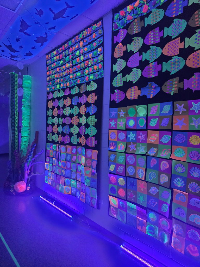 A specialized "Glow Gallery" featuring student artwork created with neon colors that pop under blacklight.