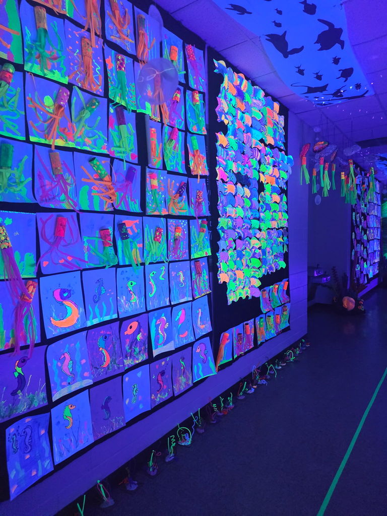 A wide view of a long hallway filled with hundreds of unique, colorful student self-portraits and paintings.
