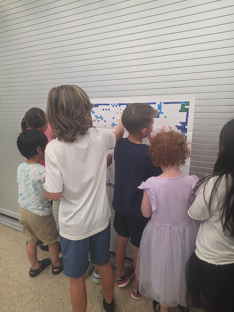 A group of elementary students gathered around a collaborative art station, excitedly working together on a project.