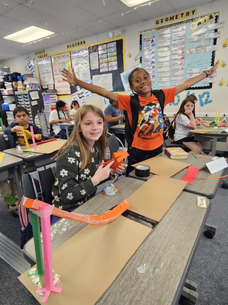 A group of students gathered around a desk, excitedly discussing and testing a collaborative building project.
