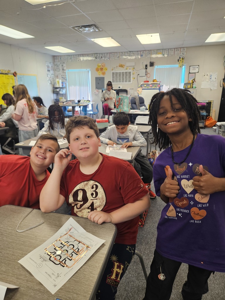 A group of students gathered around a desk, excitedly discussing and testing a collaborative building project.