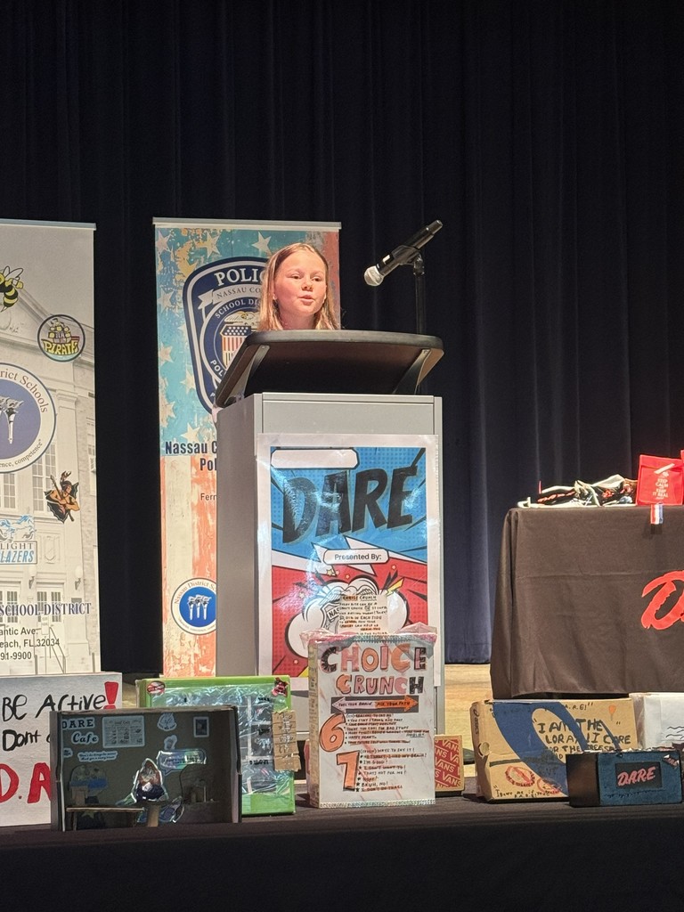 A student standing at the podium, reading their D.A.R.E. essay or commitment pledge to the audience during the graduation ceremony.