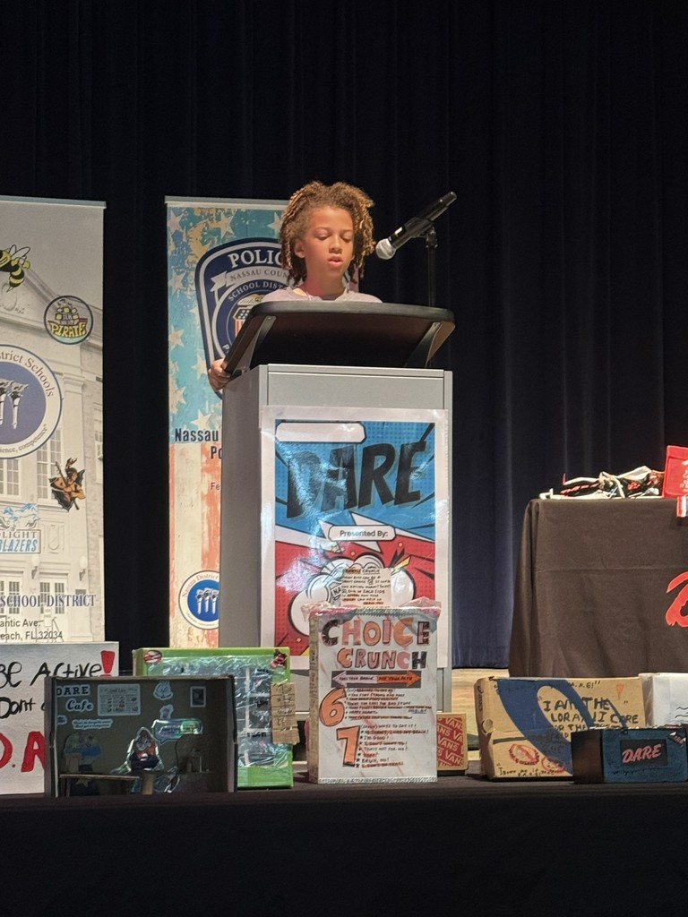 A student standing at the podium, reading their D.A.R.E. essay or commitment pledge to the audience during the graduation ceremony.