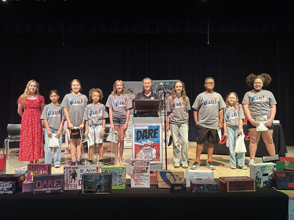 A close-up view of the stage decorated with student-made D.A.R.E. posters, graduation certificates, and educational materials used during the program at Wildlight Elementary.