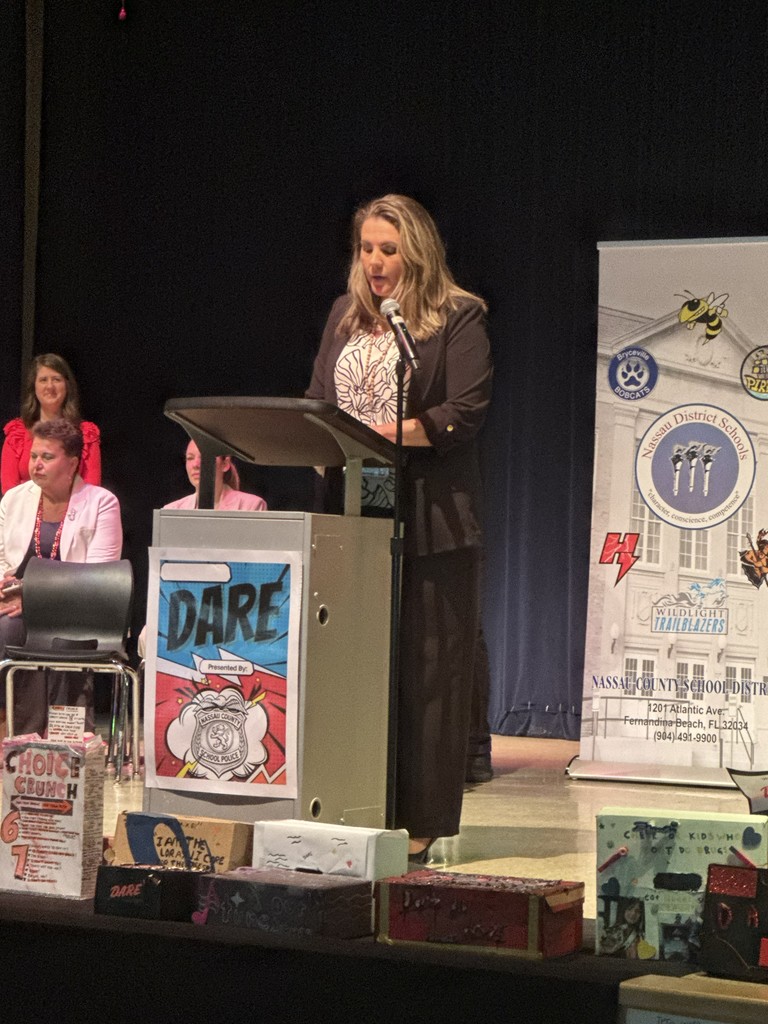 An administrator speaking at the podium, congratulating the 5th-grade Trailblazers on their hard work and dedication to the D.A.R.E. program.