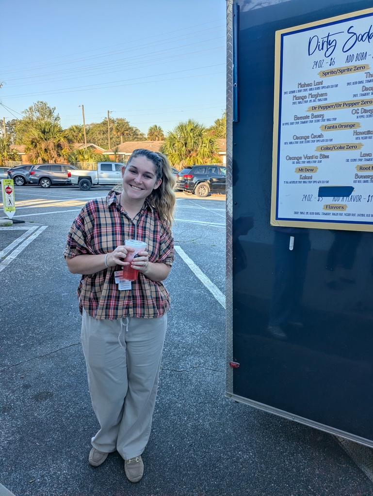 Staff member standing next to the coffee truck holding their cup of coffee.