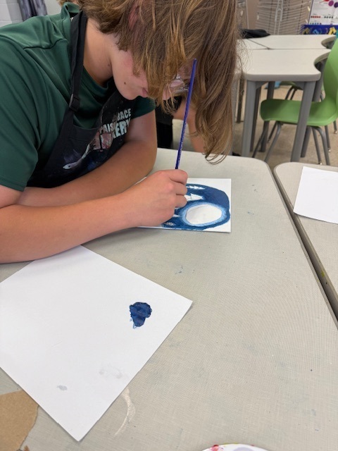 One student works on the final touches to his color scheme painting at his desk. 