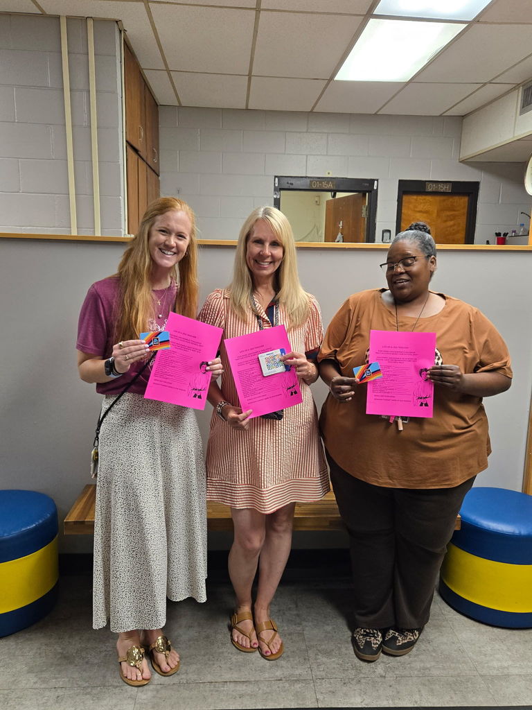 Three teachers standing with their pink unscramble challenge paper and their Aldi's gift card.
